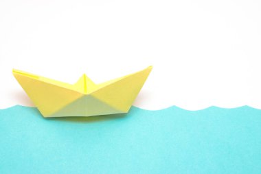 Sarı kağıt gemi mavi kağıt kesikli dalgalarda yüzüyor. Minimum konsept yaz ve seyahat düzlüğü, taklit alanı