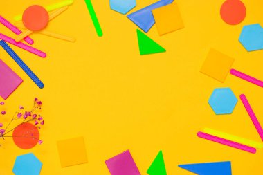 Okul konseptine geri dönelim. Düz kat. Sarı arkaplanda renk sayan çubuklar ve plastik geometrik şekiller.