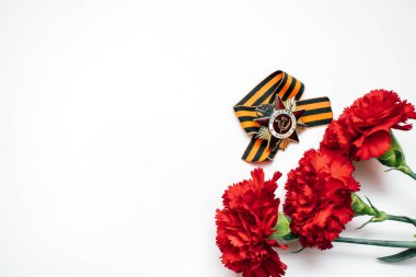 Rusya Zafer Günü anısına 9 Mayıs 'ın şenlikli arka planı. Kırmızı karanfiller, Rus vatanseverlik savaşının beyaz arka planda yazdığı kırmızı yıldızın emri. Uzayı kopyala.