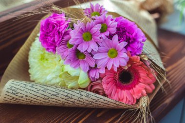 Renkli sarmal buket büyük pembe gül, beyaz amiriliz, mercan gerbera, buğday kulakları, mor karanfil ve el işi kağıdında kasımpatı.