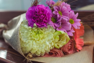 Renkli sarmal buket büyük pembe gül, beyaz amiriliz, mercan gerbera, buğday kulakları, mor karanfil ve el işi kağıdında kasımpatı.