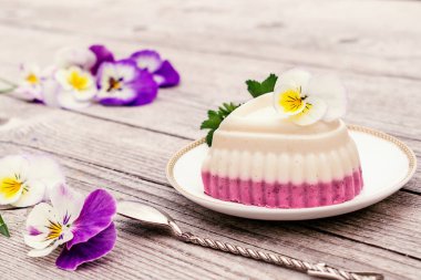  Süzme peynir, agar-agar ve kremalı bir kalp şeklindeki sufle ahşap bir arka planda beyaz bir tabakta. Menekşe çiçekleri kompozisyonu süslüyor. Sağlıklı yiyecek ve sağlıklı tatlı kavramı dışında.