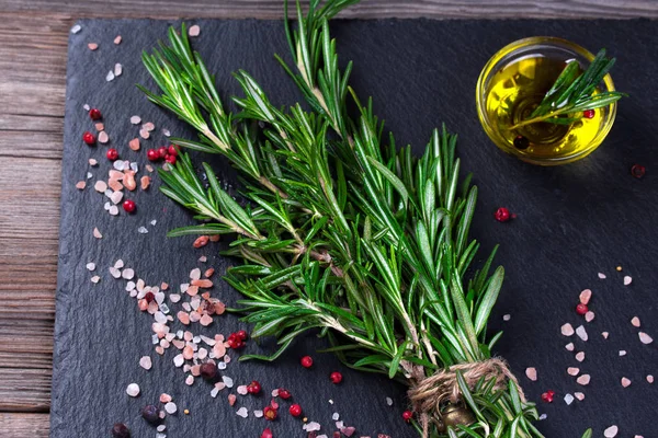 Rosmarinpflanze, Salz und Gewürze auf schwarzer Schiefertafel — Stockfoto