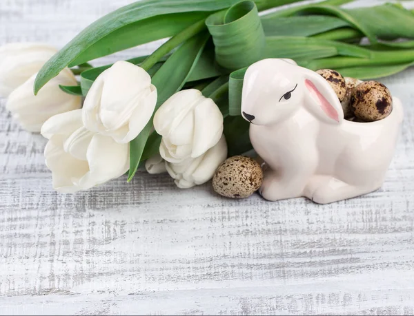 Пасхальный состав с яйцами, весенними тюльпанами и фарфоровым пасхальным кроликом на старом деревянном столе — стоковое фото