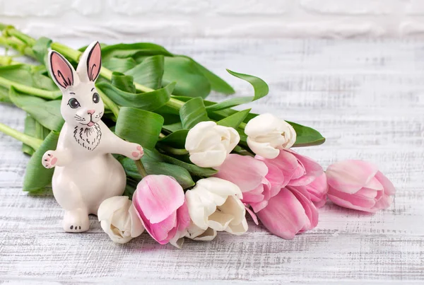 Пасхальный состав с яйцами, весенними тюльпанами и фарфоровым пасхальным кроликом на старом деревянном столе — стоковое фото