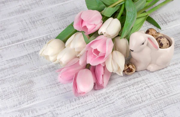 Composição de Páscoa com ovos, tulipas de primavera e coelho de porcelana na mesa de madeira velha — Fotografia de Stock