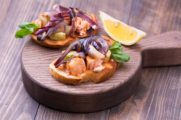 Kavrulmuş sebze, somon, soğan ve bir kesme tahtası üzerinde otlar ile İtalyan bruschetta — Stok fotoğraf