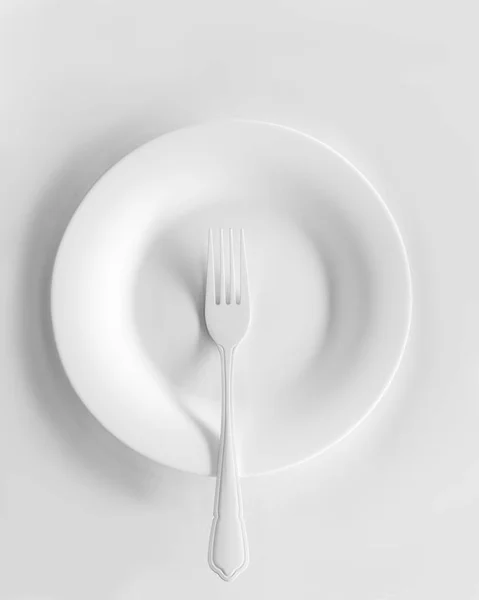 Fork over the empty white ceramic plate — Stock Photo, Image