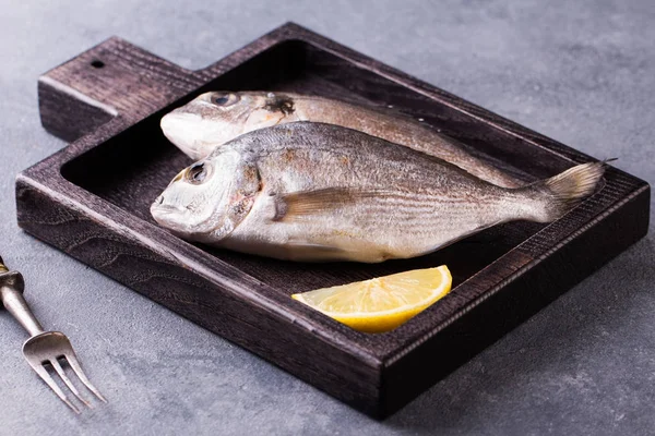 Fresh raw sea bream fish decorated with lemon slices — Stock Photo, Image