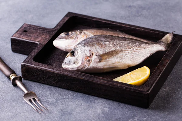 Fresh raw sea bream fish decorated with lemon slices — Stock Photo, Image