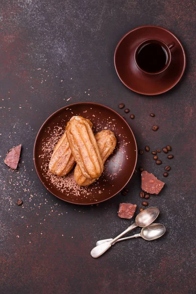 Schokolade eclair und Kaffeetasse auf dunklem Hintergrund — Stockfoto