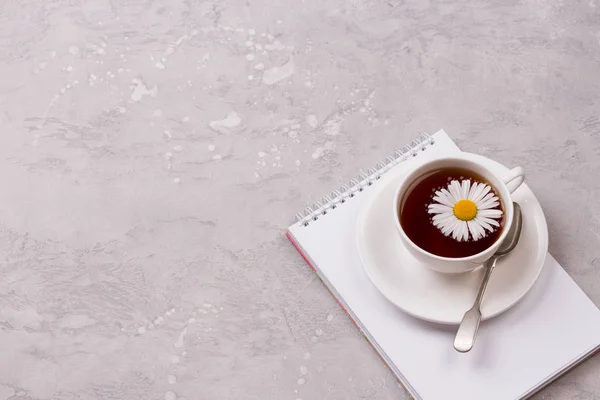 cup of tea with chamomile flowers on grey stone background