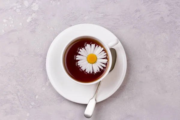 Чашка чая с ромашковыми цветами на фоне серого камня — стоковое фото