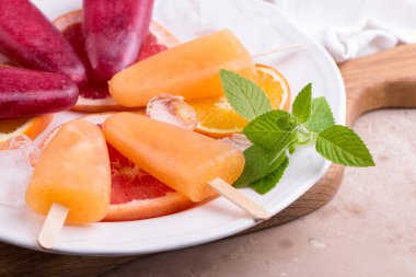 Pembe ve turuncu buzlu şeker gri taş zemin üzerine kırmızı portakal ile.