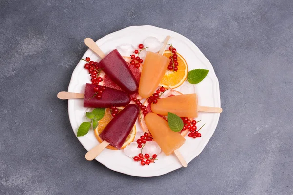 Popsicle rose et orange avec oranges rouges sur fond de pierre grise . — Photo