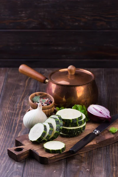 Zucchini with slices and onion on a wooden table. — Stock Photo, Image