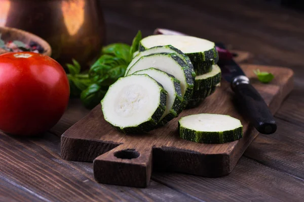 Zucchini with slices and onion on a wooden table. — Stock Photo, Image