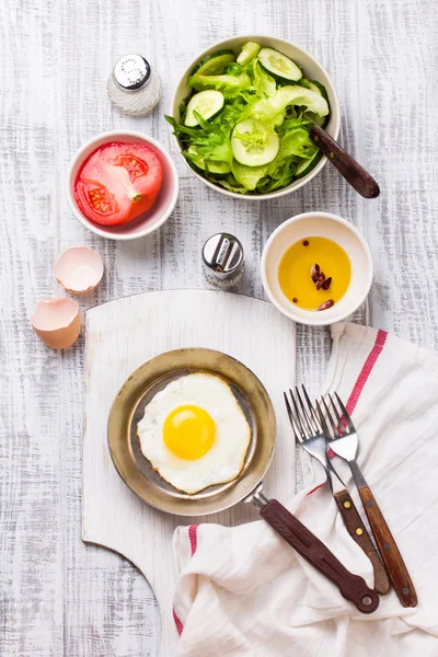 Fried eggs in a frying pan with tomatoes and vegetable salad for breakfast — Stock Photo, Image
