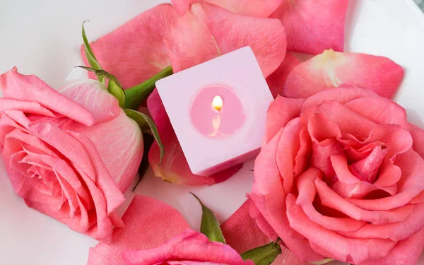 Roze bloemblaadjes van rozen en brandende kaarsen — Stockfoto
