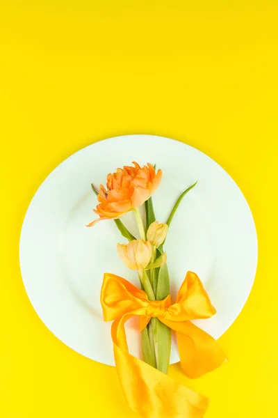 Schöne gelbe Tulpen in rundem Teller auf gelbem Hintergrund. Minimalkonzept — Stockfoto