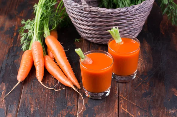 Färsk pressade morotsjuice i glas på trä bakgrund. — Stockfoto