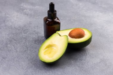Avokado ve avokado yağı gri arka planda