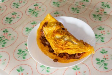 Omlet, masada beyaz bir tabakta servis edilen et ve soğanlı nefis bir omlet..