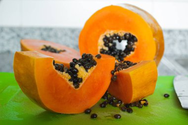 Yeşil bir kesme tahtasında kesilmiş lezzetli turuncu papaya meyvesi.