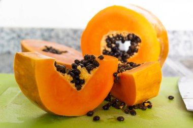 Yeşil bir kesme tahtasında kesilmiş lezzetli turuncu papaya meyvesi.