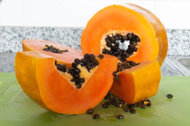 Yeşil bir kesme tahtasında kesilmiş lezzetli turuncu papaya meyvesi.