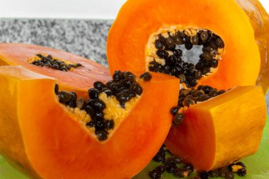 Yeşil bir kesme tahtasında kesilmiş lezzetli turuncu papaya meyvesi.