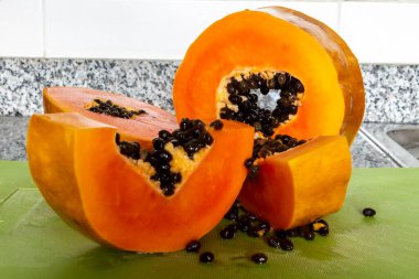Yeşil bir kesme tahtasında kesilmiş lezzetli turuncu papaya meyvesi.