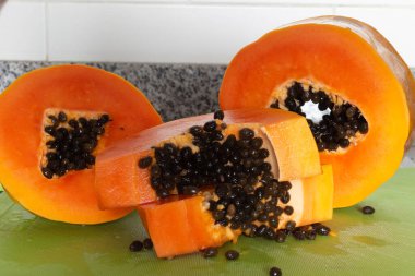 Yeşil bir kesme tahtasında kesilmiş lezzetli turuncu papaya meyvesi.
