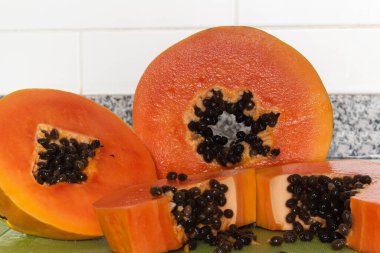 Yeşil bir kesme tahtasında kesilmiş lezzetli turuncu papaya meyvesi.