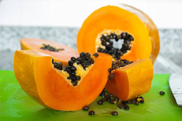 Yeşil bir kesme tahtasında kesilmiş lezzetli turuncu papaya meyvesi.