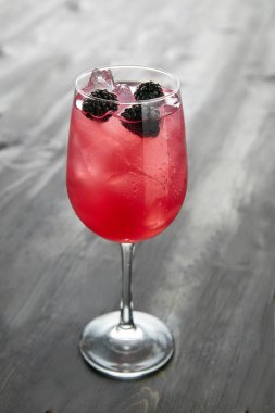 Kırmızı meyve suyu, alkolsüz, bir bardak Sangria yabanmersini kokteyli, ahşap masa manzaralı, izole edilmiş.