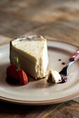 Çatallı ve dilimlenmiş çilekli cheesecake, yan görüş. Bir tabak ve çatallı cheesecake.. 