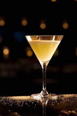 Martini bardağında zencefilli kokteyl, kamış şekerli sarı kokteyl, koyu arkaplanda. Koyu arkaplanda martini bardağında turunç kokteyli, sığ..