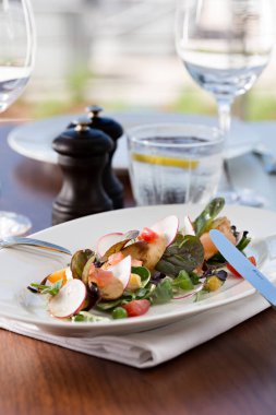 Izgara ızgara ahtapot salatası, servis masasında çatal ve bıçakla beyaz bir tabakta. Izgara ahtapot, patates ve sebzeli aperatif..