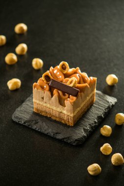 Taş tahtada karamelli fındıklı tart gevşek fındık kenarlı. Mini fındık ve çikolatalı tart siyah arka planda izole edilmiş..