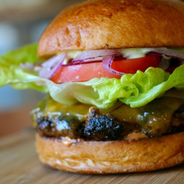 Domates ve marullu sulu burger. Sokak yemeği. Ahşap masada ızgarada pişmiş taze ızgara biftekli hamburger. 