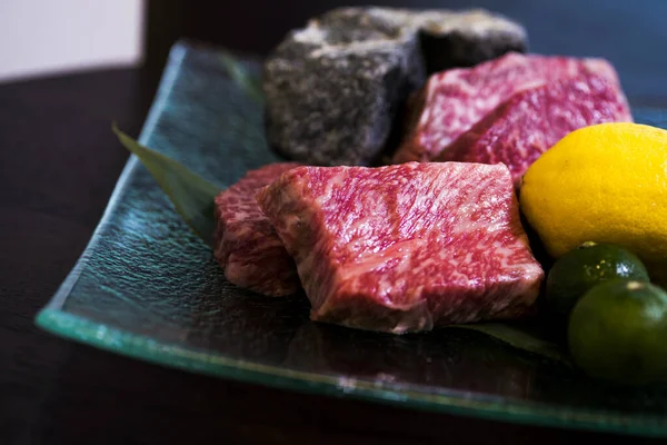 Japanese marbled meat on a plate with lemon and lime Kobe beef Wagyu beef Raw fresh marbled meat Steak. Premium meat A4 grade.