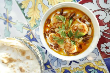 Limonlu ve sarımsaklı kremalı çorba, karides ve çam fıstığıyla süslenmiş, yukarıdan, ekmekli bir masada. Karidesli peynir çorbası. Sarı çorba limon ve maydanozla süslenir. Sağlıklı, organik.