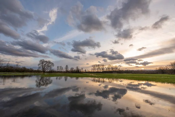 Cloudy sky reflecting in the water in a flooded meadow