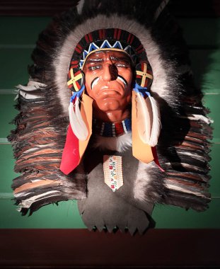 Barın içindeki ahşap bir duvarda asılı duran odaksız Hint maskesi. 