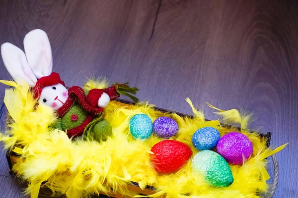 Пасхальный кролик, цветные яйца и желтые перья в корзине . — стоковое фото