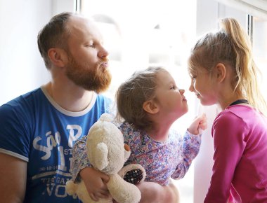 Babam pencere pervazında oturan kızlarıyla oynuyor.