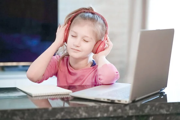 Młody uśmiechnięty, jasnowłosy maluch słuchający muzyki ze słuchawkami. — Zdjęcie stockowe