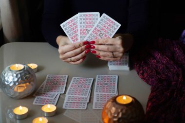 Tarot okuyucusu yanan mumların yanında tarot kartları topluyor..