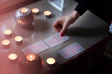 Tarot okuyucusu yanan mumların yanında tarot kartları topluyor..